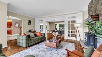 A spacious living room with a large green sofa, a wooden coffee table, and a stone fireplace.