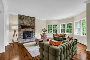 Ein Wohnzimmer mit Kamin aus Stein, einem grünen Sofa und Holzboden.
