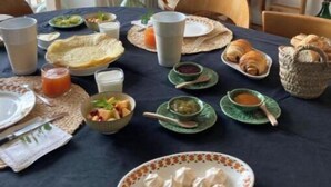 Una mesa de comedor dispuesta con diversos platos, incluyendo pasteles y un bol de fruta.
