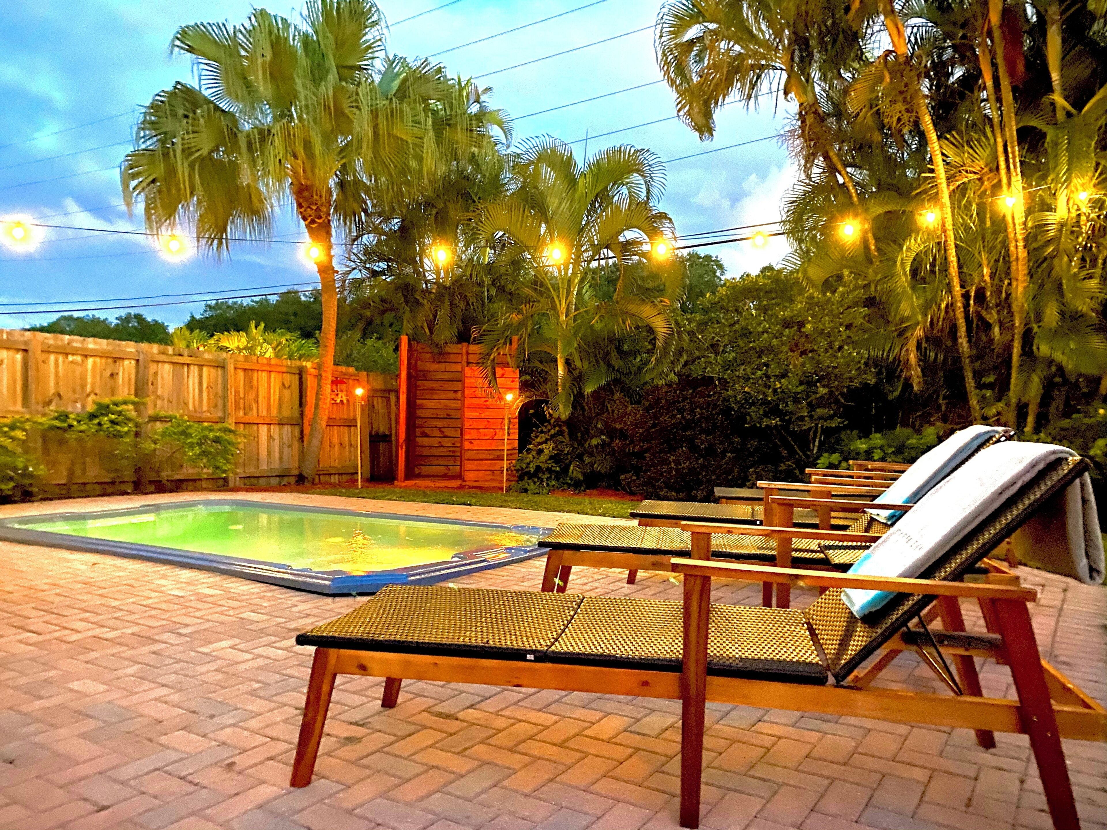 A pool area with lounge chairs and a wooden fence.