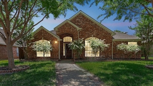 A brick house with a central entrance, two side wings, and a covered porch. - Family Fun Retreat: Pool & Entertainment Haven! 4 Bedroom Home by RedAwning (Frisco)