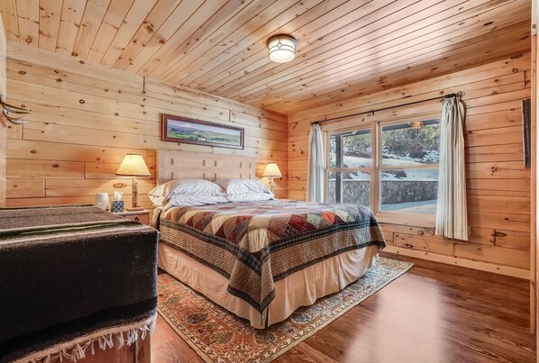 Cozy bedroom with a large bed, bedside lamps, and a view of the outdoors through the window.
