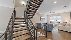 A modern interior with a wooden staircase, a living area with a sofa and coffee table, and a ceiling fan. - Cityscape Retreat 2 Bedroom Townhouse by RedAwning (Sarasota)