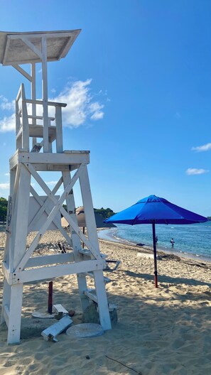 A lifeguard tower and a blue umbrella on a sandy beach. - Studio Accommodation Near the Malecón Puerto Plata (Puerto Plata)
