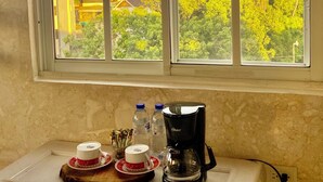 A kitchen area with a window overlooking a residential neighborhood, a coffee maker, and two cups on a tray.