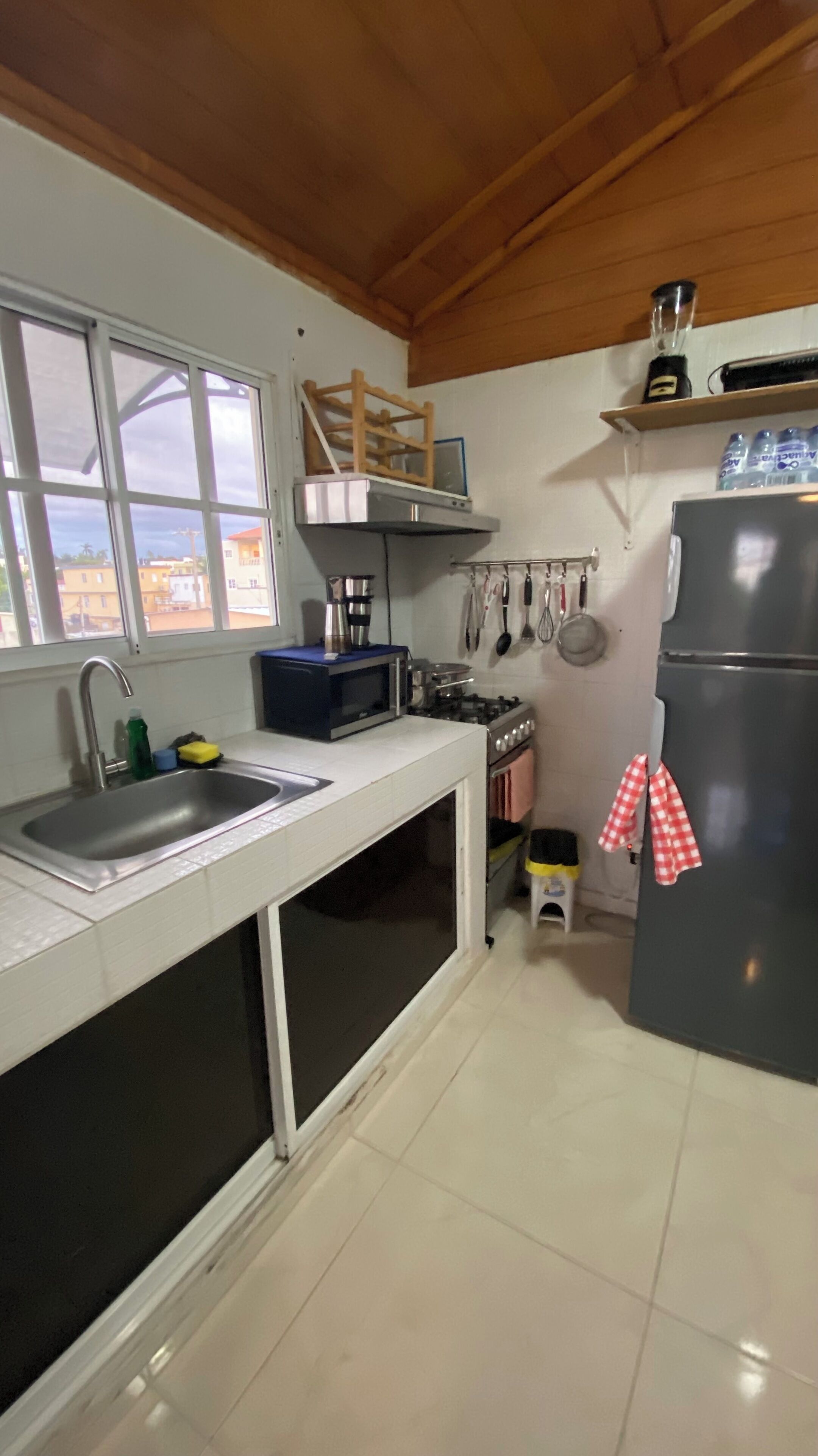 A compact kitchen with a sink, stove, microwave, and refrigerator.