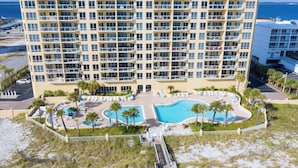 A high-rise hotel with multiple balconies, a pool area with palm trees, and a beach view. - Beautiful 3 Bed, 2 Bath Gulf Front Condo/Free Platinum Beach Service! (Pensacola Beach)