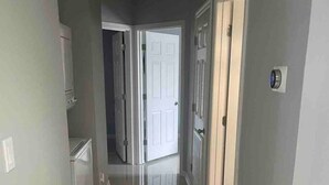 A hallway with a tiled floor, white doors, and a light switch on the wall. -  2BR Elegant Apartment for 8, Edinburg Texas (Edinburg)