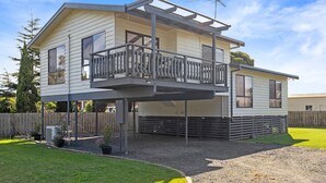 A two-story house with a balcony, a fenced yard, and a gravel driveway.