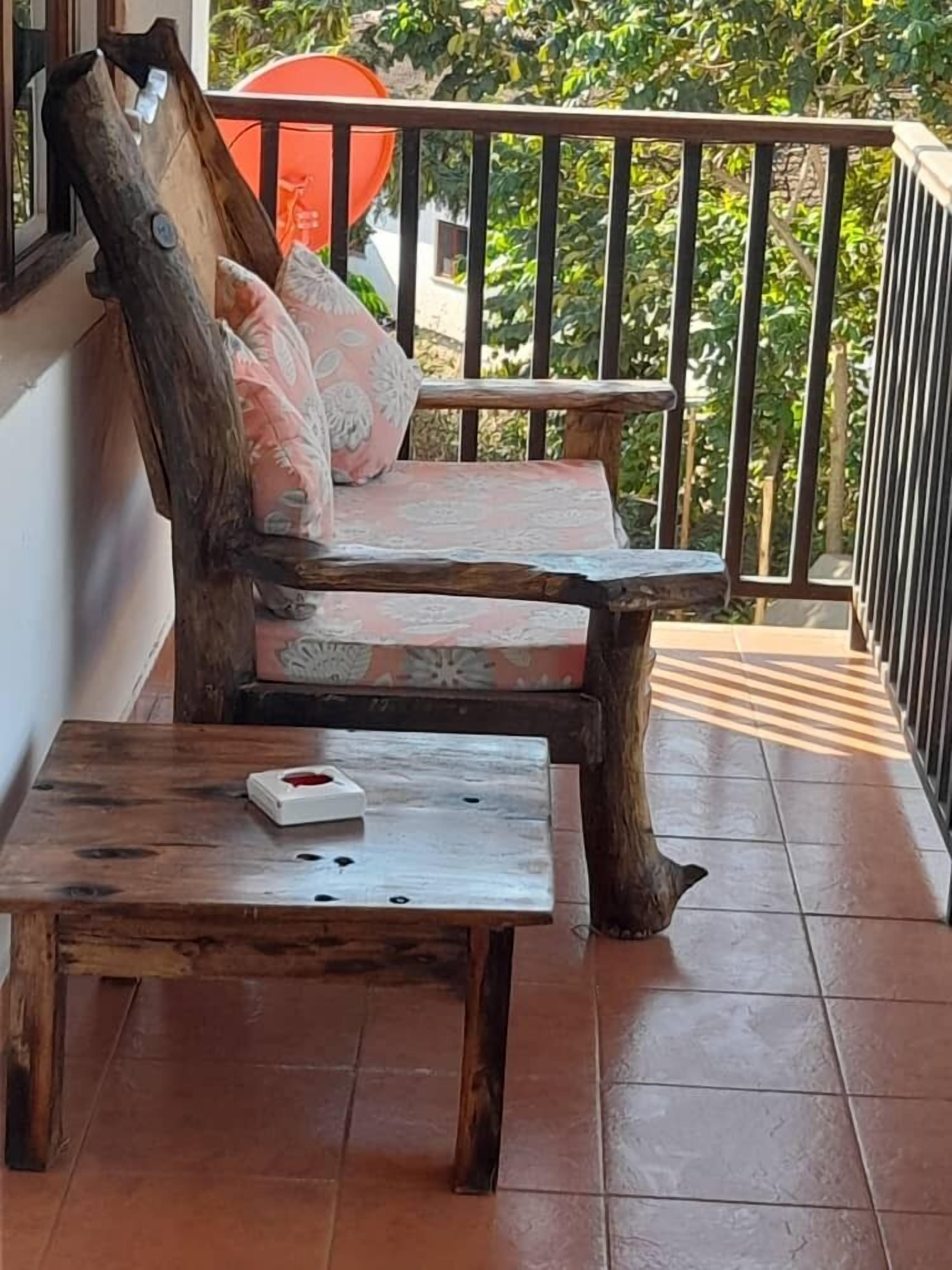 A wooden bench with cushions, a small wooden table, and a tiled floor.