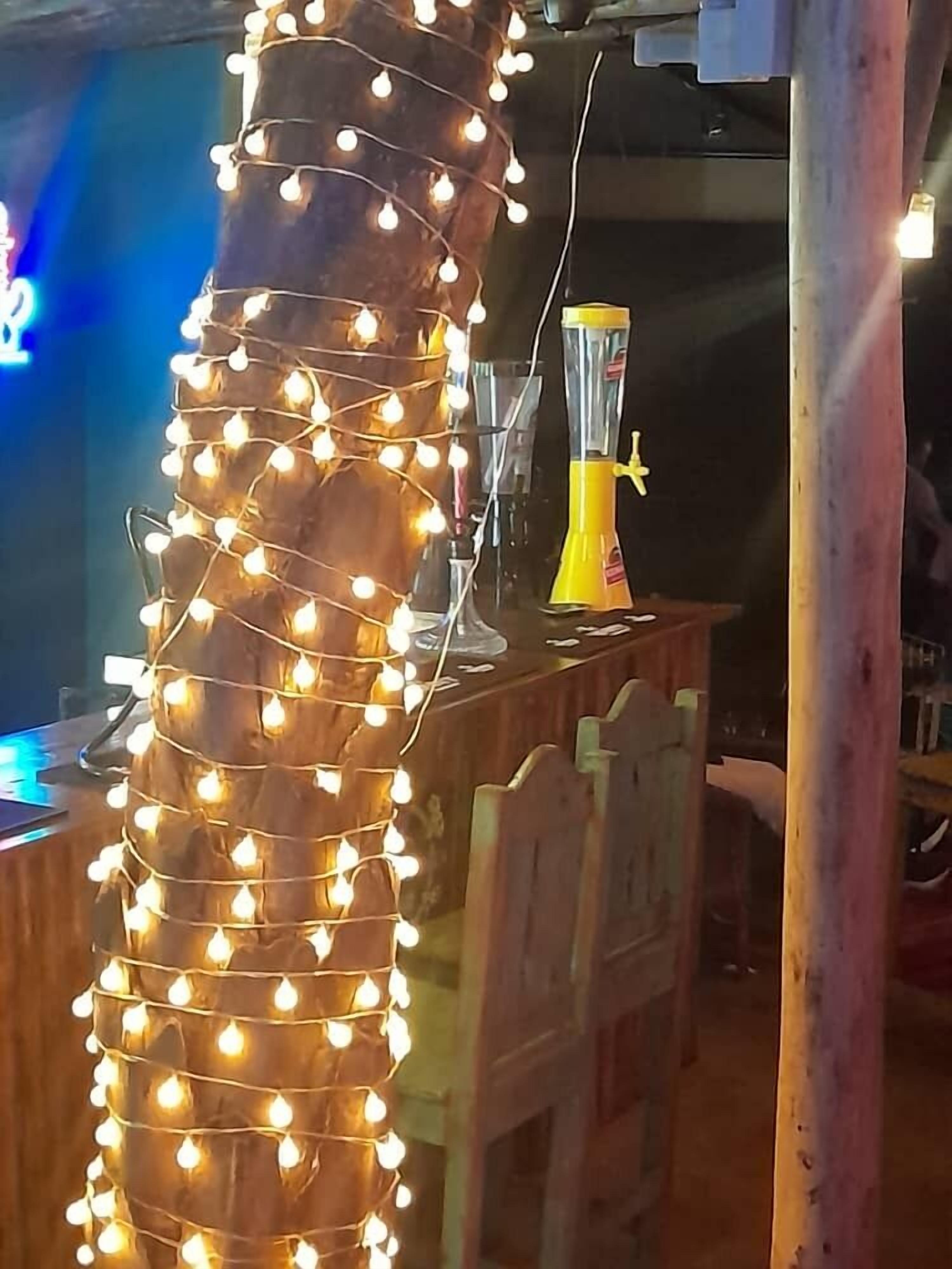 Un pilastro di legno decorato con luci a stringa, un frullatore giallo su un bancone e una sedia di legno in una stanza con una parete blu.