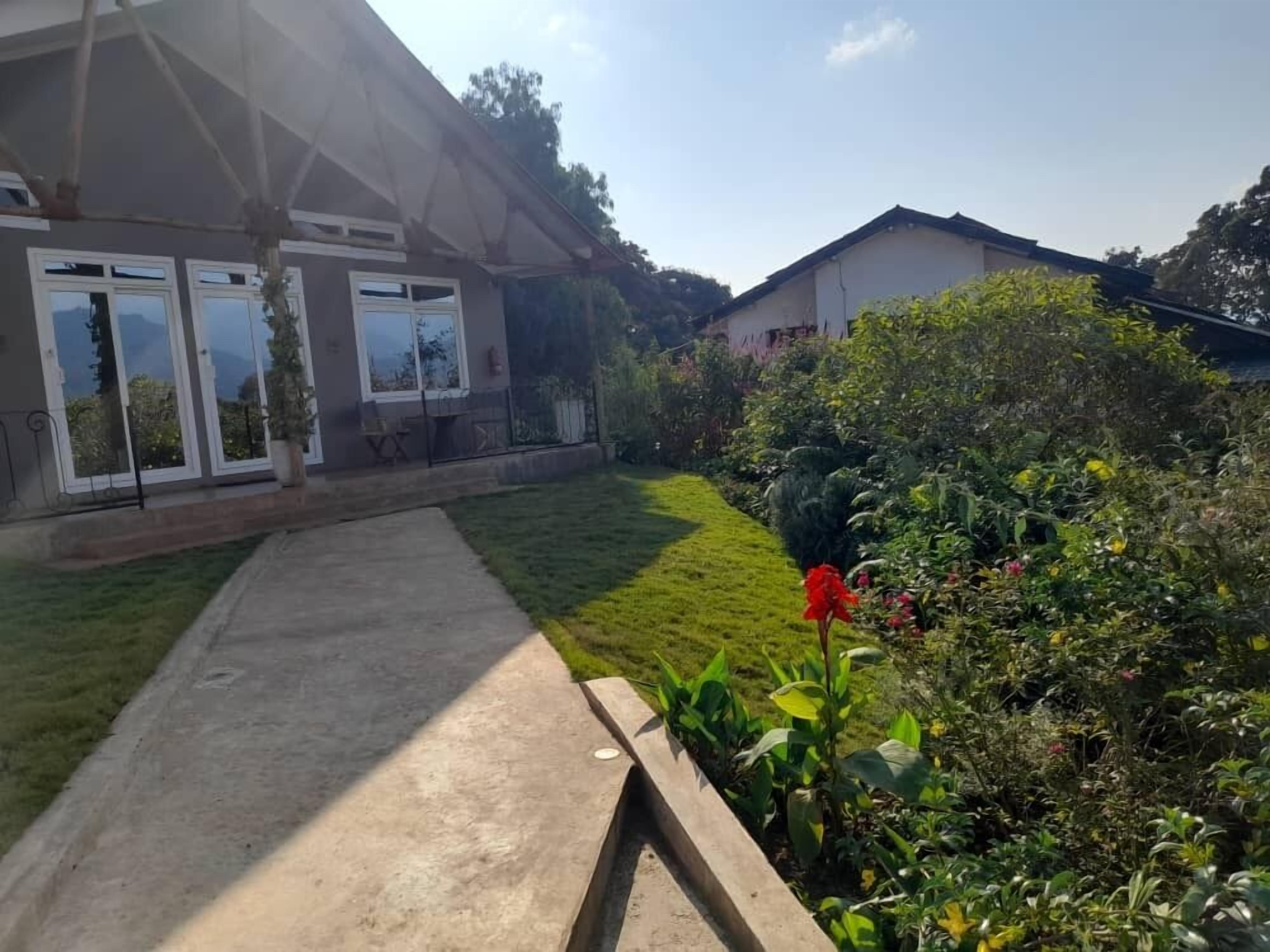 A residential property with a paved driveway leading to a house with large windows and a covered patio area.