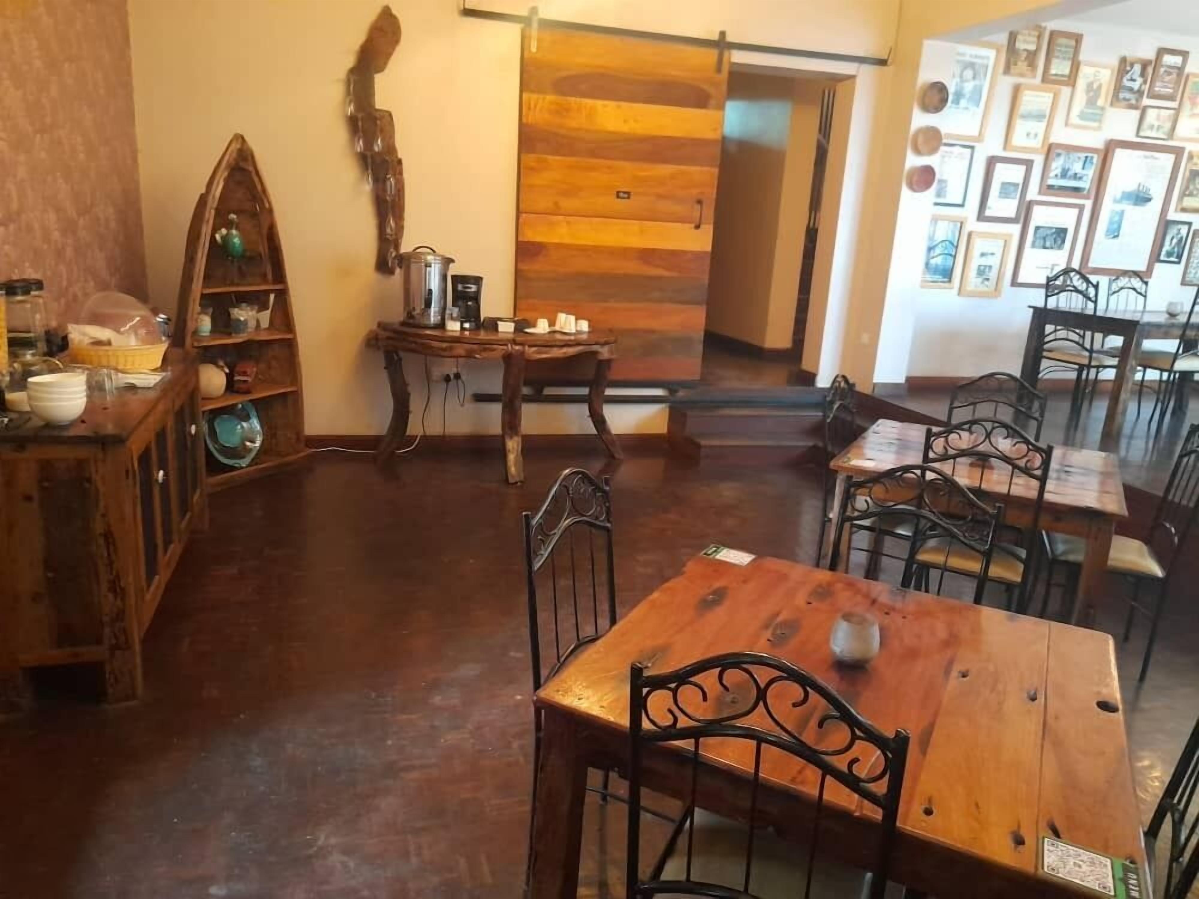 Un comedor rústico con mesas y sillas de madera, una estación de café y una pared decorada con cuadros.