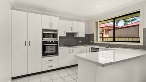 A modern kitchen with white cabinetry, stainless steel appliances, and a large window providing a view of the outside.
