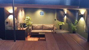 Een gezellige woonkamer met een leren bank, houten vloeren en potplanten.