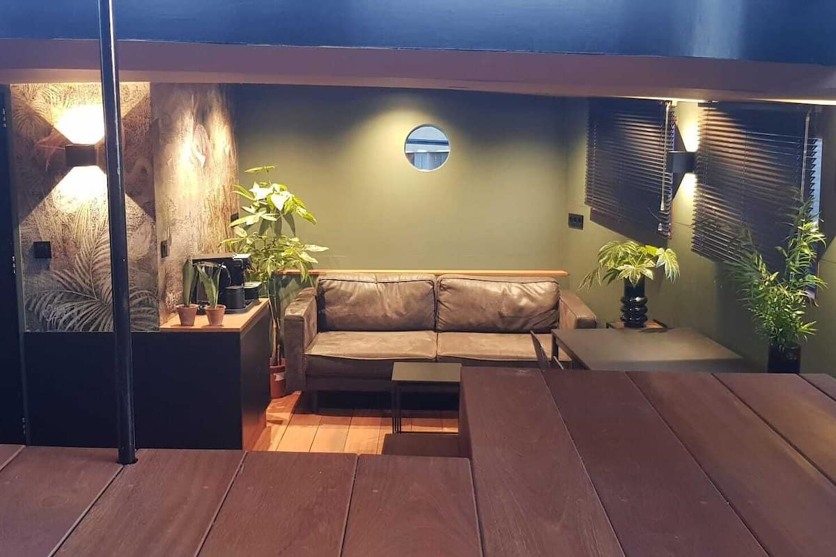 A cozy living room with a leather sofa, wooden flooring, and potted plants.