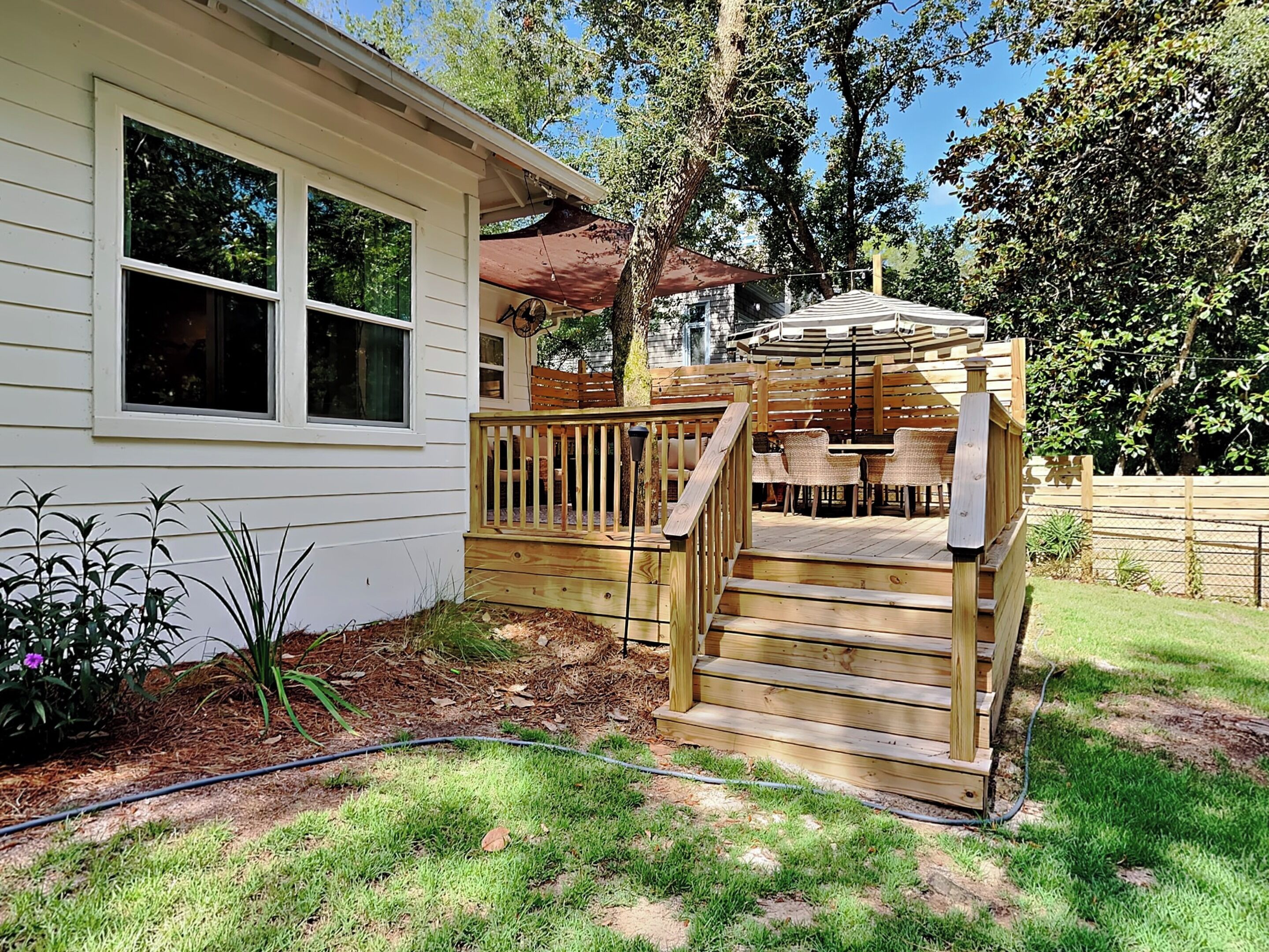 A wooden deck with outdoor seating and a small staircase leading to a covered area.