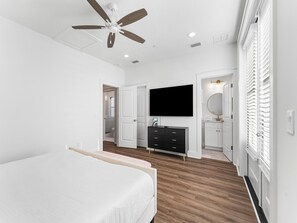 A bedroom with a bed, a TV, a dresser, and a ceiling fan. - Coastal Haven B by Resort Collection (Panama City Beach)