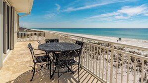 Ein Balkon mit Tisch und Stühlen mit Blick auf einen Strand.