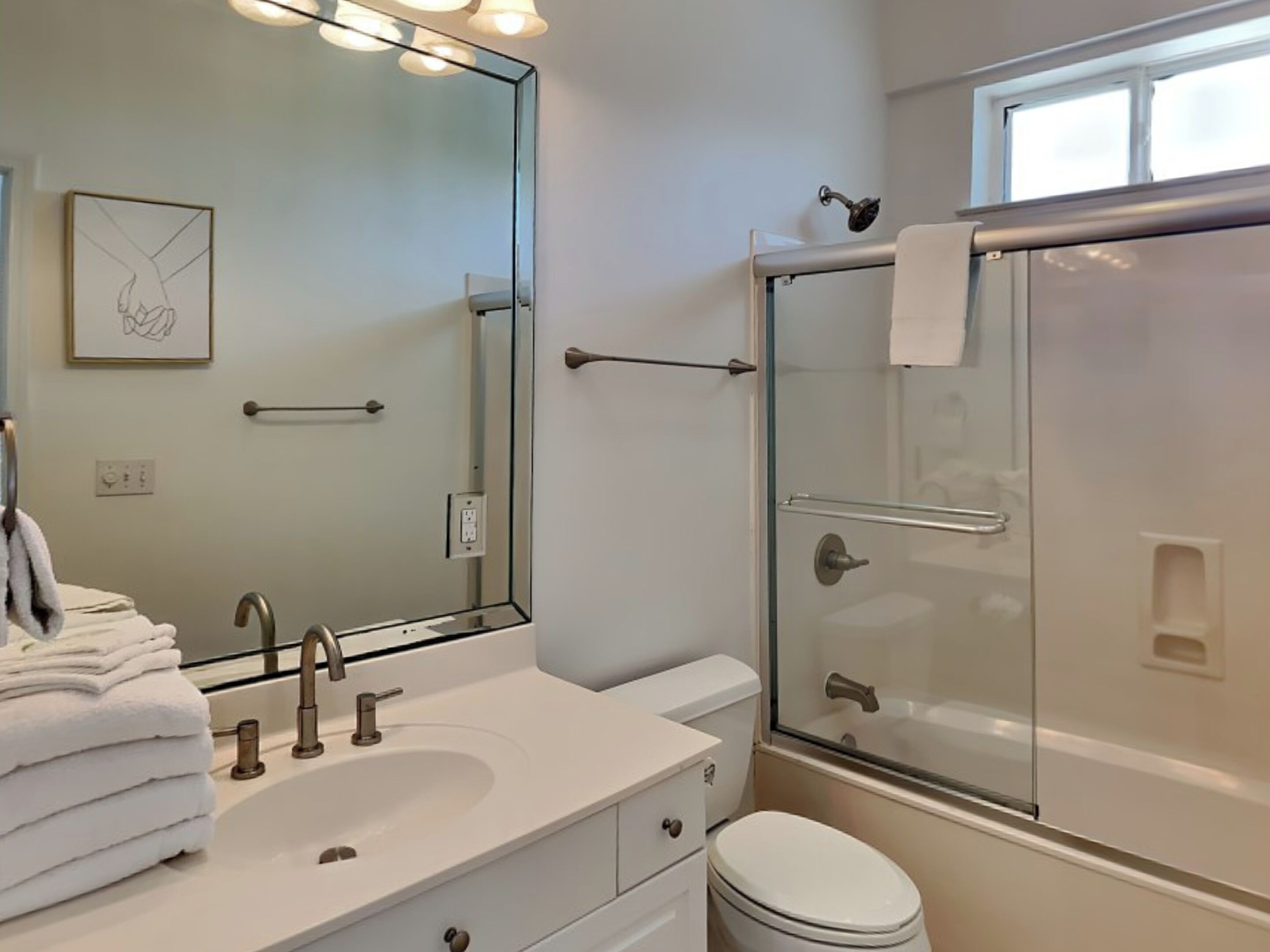 Une salle de bain moderne avec un lavabo, un miroir et une douche en verre.