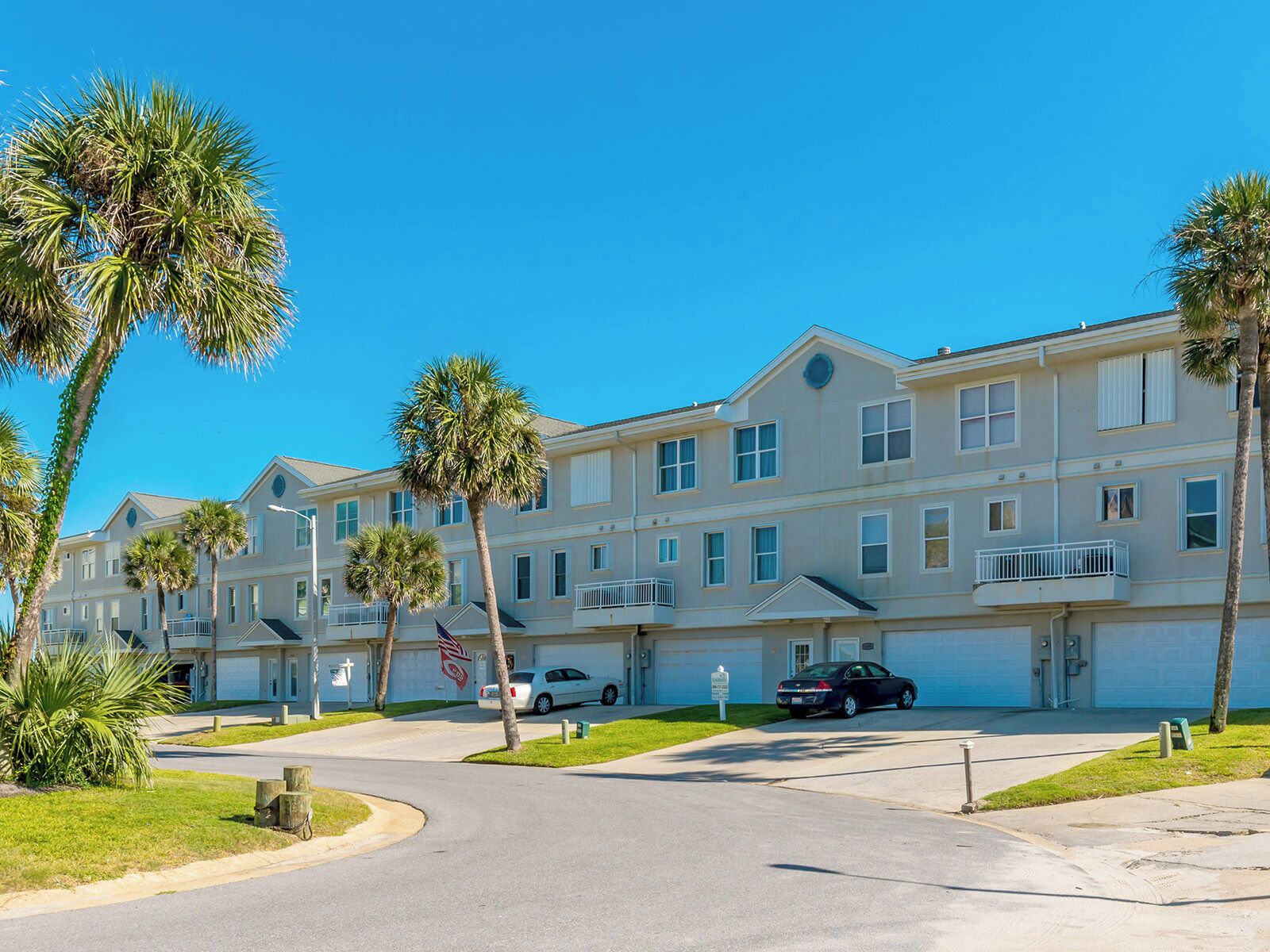 A multi-story residential building with a central courtyard, surrounded by palm trees.