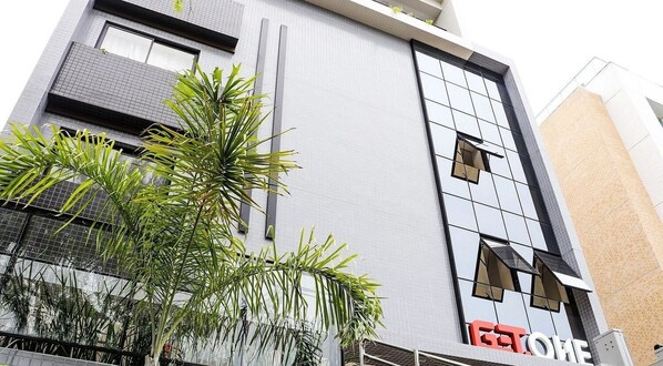 A modern building with a glass facade, a visible entrance, and a sign that reads 'HOTEL'. - Get One Suites (João Pessoa)