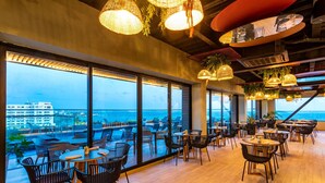 Een modern restaurant met grote ramen met uitzicht op zee en de skyline.