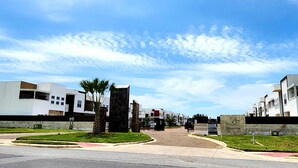 Una zona residencial moderna con arquitectura contemporánea, un camino central y cielo despejado.