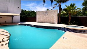 Piscina con muro de piedra con el letrero "PALMS" y zona de hidromasaje.