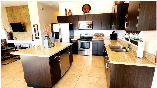 Una cocina moderna con gabinetes de madera oscura, electrodomésticos de acero inoxidable y encimera de granito.