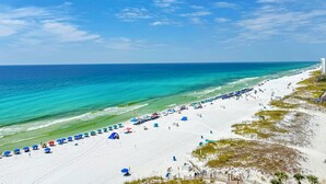 A beach with white sand, clear turquoise water, and a clear sky.