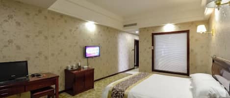 A hotel room with a bed, a desk, a television, and a window with blinds.