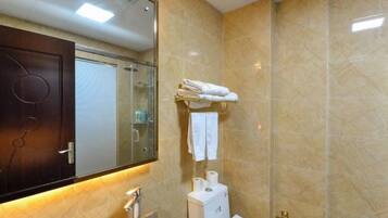 Un baño con lavamanos, espejo, toallero y zona de ducha.