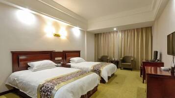 A hotel room with two beds, a desk, a chair, and a television.