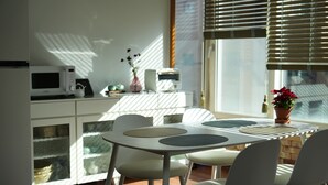 Una cocina moderna con alacenas blancas, un microondas y un comedor con mesa y sillas.