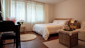 Un dormitorio con cama, mesita de noche, lámpara y un pequeño taburete de madera.