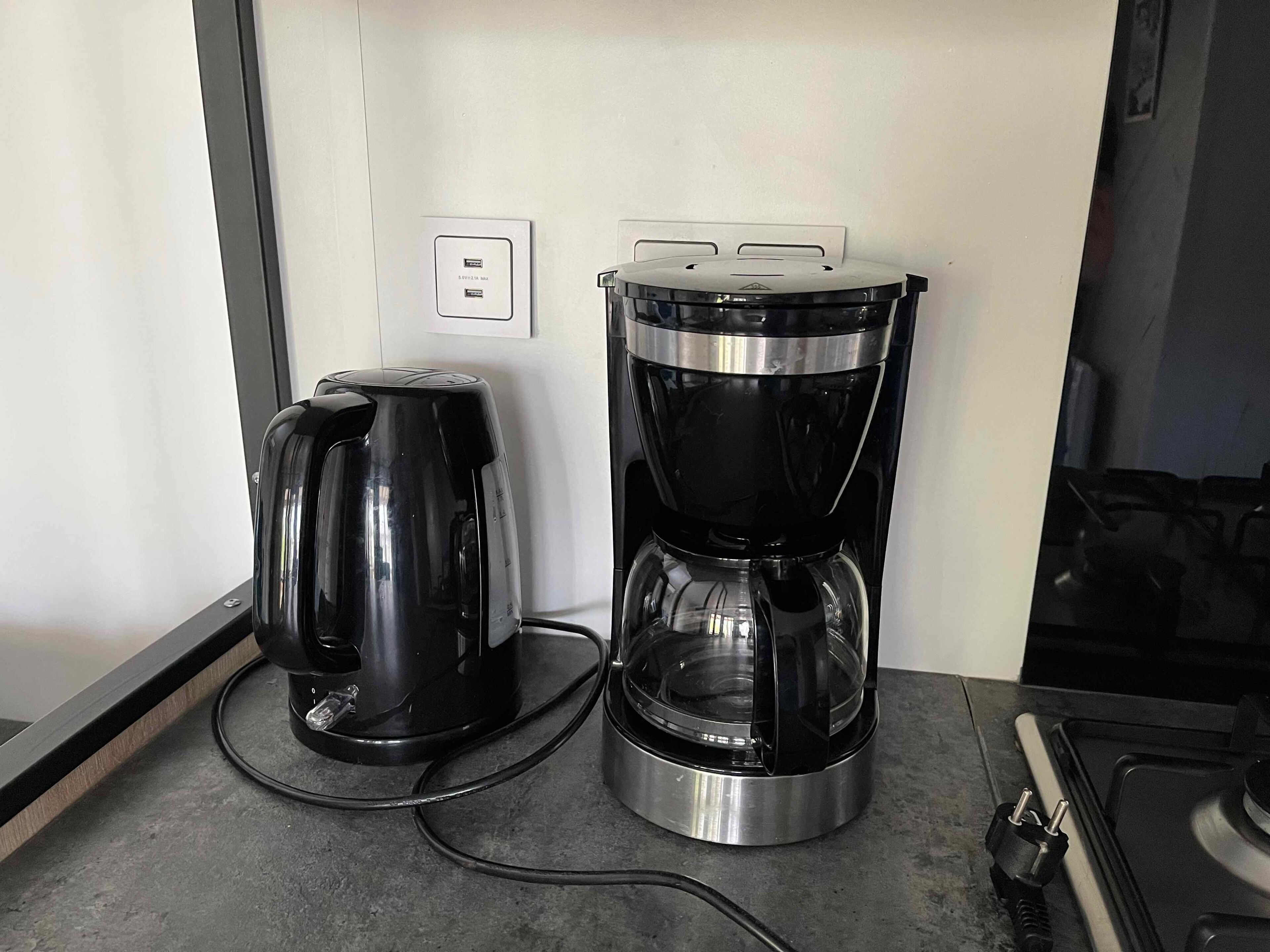 Une cuisine équipée d’une machine à café et d’une bouilloire posées sur le plan de travail.