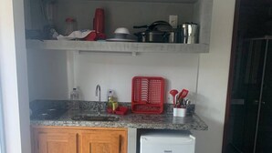 A compact kitchen with wooden cabinets, a built-in sink, and a white refrigerator. - Casas de Juan (Cairu)