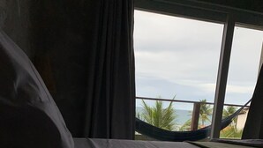 A bed with a view of the ocean and a hammock outside the window. - Casas de Juan (Cairu)