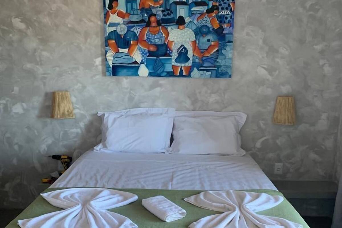 Ein Hotelzimmer mit einem Bett, einem Bild an der Wand und je einer Lampe auf beiden Seiten des Bettes.