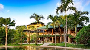 A resort with a swimming pool, palm trees, and a building with multiple balconies. - Tombo House (Diani Beach)