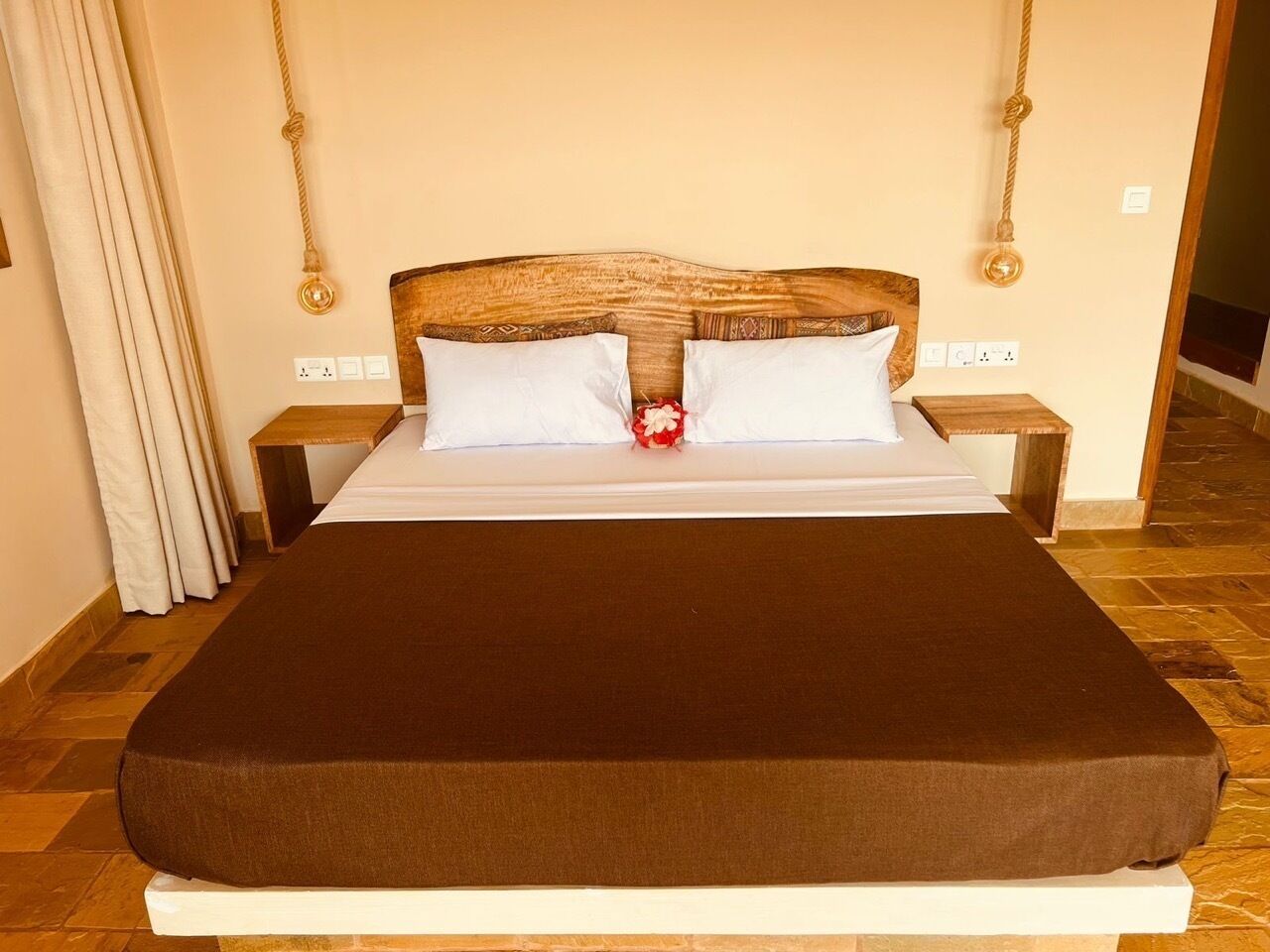 A bed with a brown mattress, white pillows, and a wooden headboard. There are two bedside tables with lamps.