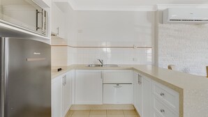 Et moderne køkken med hvide skabe, rustfrie stålapparater og et flisebeklædt bagpanel.