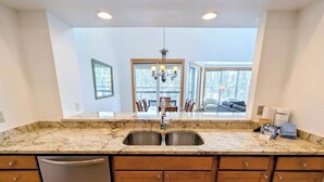 A kitchen with granite countertops, stainless steel sinks, wooden cabinets, and a dishwasher. - Large Bright Condo w/ Hot Tub, Pool & Shuttle (Keystone)