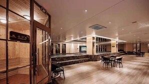 Un espace intérieur spacieux doté d’un plancher en bois, d’un coin salon avec des tables et des chaises, et d’un comptoir avec un tableau affichant le menu.