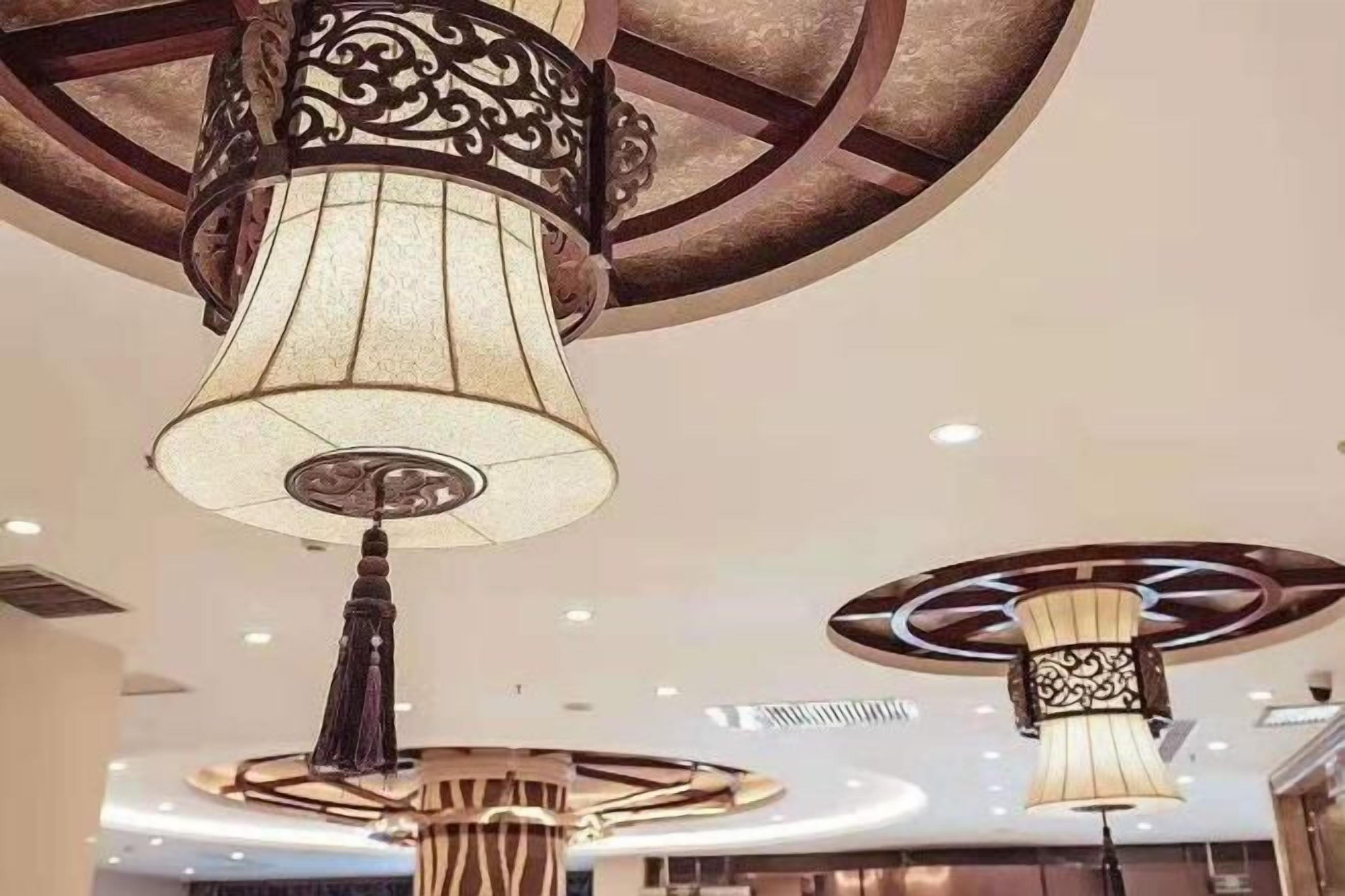 A ceiling with decorative chandeliers featuring intricate metalwork and lampshades.
