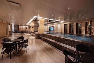 A hotel lobby with a pool, seating area, and a reception desk.