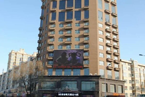 A tall building with multiple balconies and a large billboard advertising a movie. - Xinwei Hot Spring Hotel (Suihua)