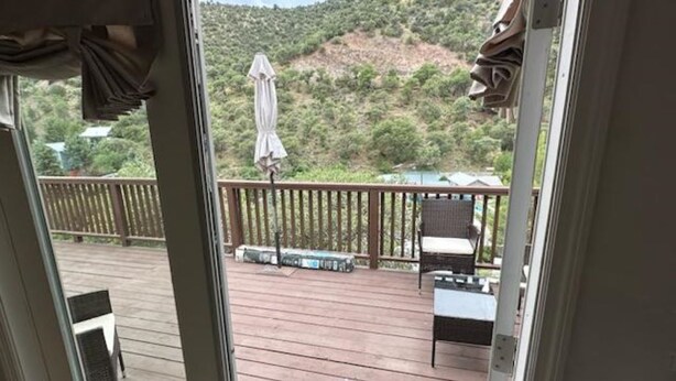 A wooden deck with outdoor furniture, including chairs and a table, overlooking a hilly landscape. - LUXURY 2-bedroom house in brilliant Bisbee with BREATHE taking views (Bisbee)