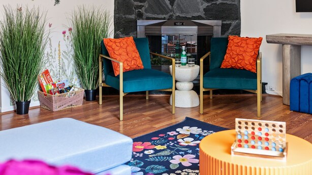 Un salon avec deux fauteuils turquoise, une table basse et un mur décoratif.